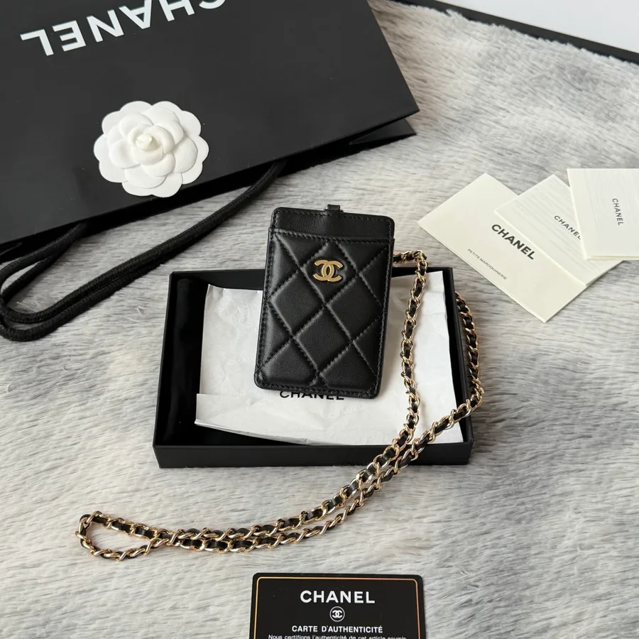 Chanel card holder in black quilted leather with gold-tone hardware on a light background