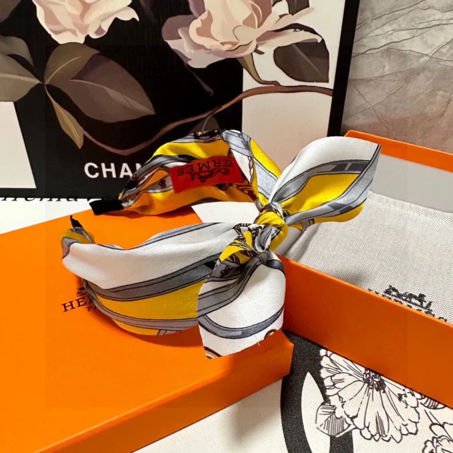 Narrow striped silk ribbon in yellow, white and grey with a red brand label, tied in a knot
