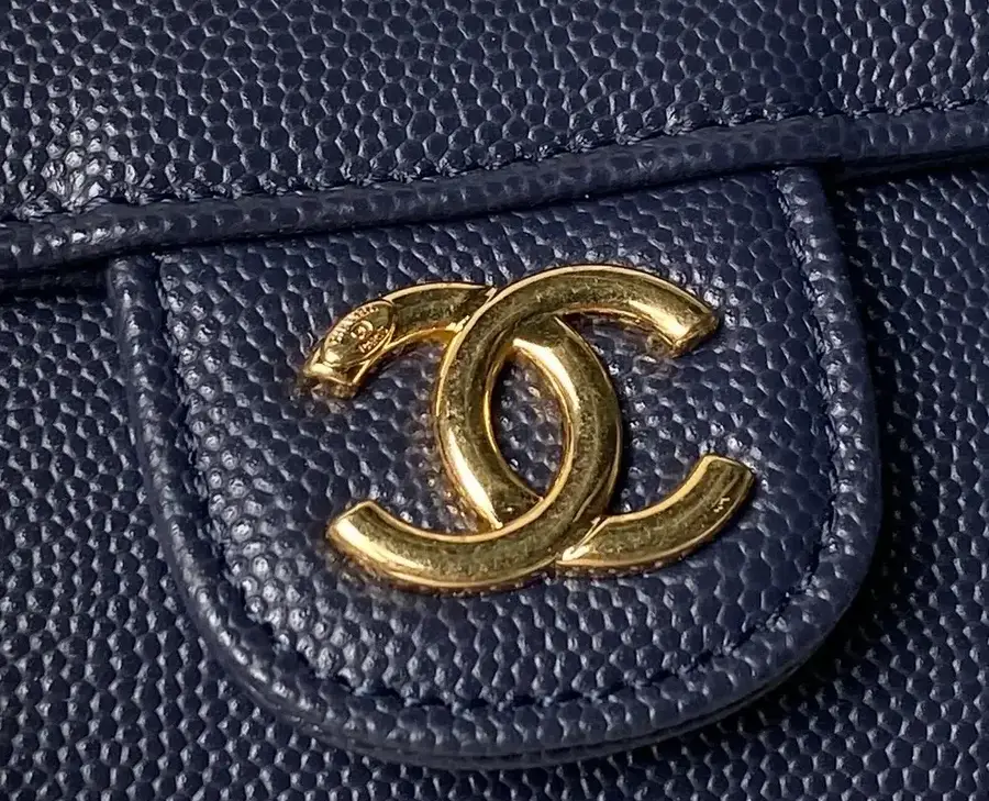 Close-up of a navy quilted flap in grained calfskin with a gold-tone CC turn-lock, showing the raised pebble texture that gives caviar its name