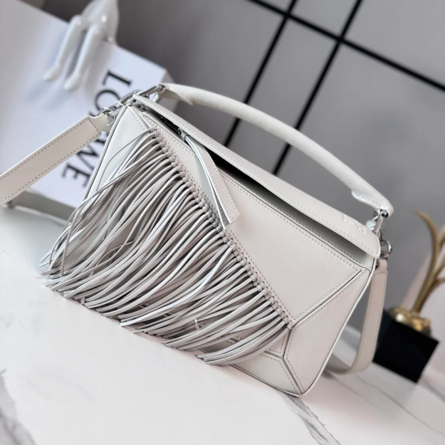 White LOEWE Puzzle-style bag with geometric panel seams, a long leather fringe down the front, a top handle and a detachable shoulder strap