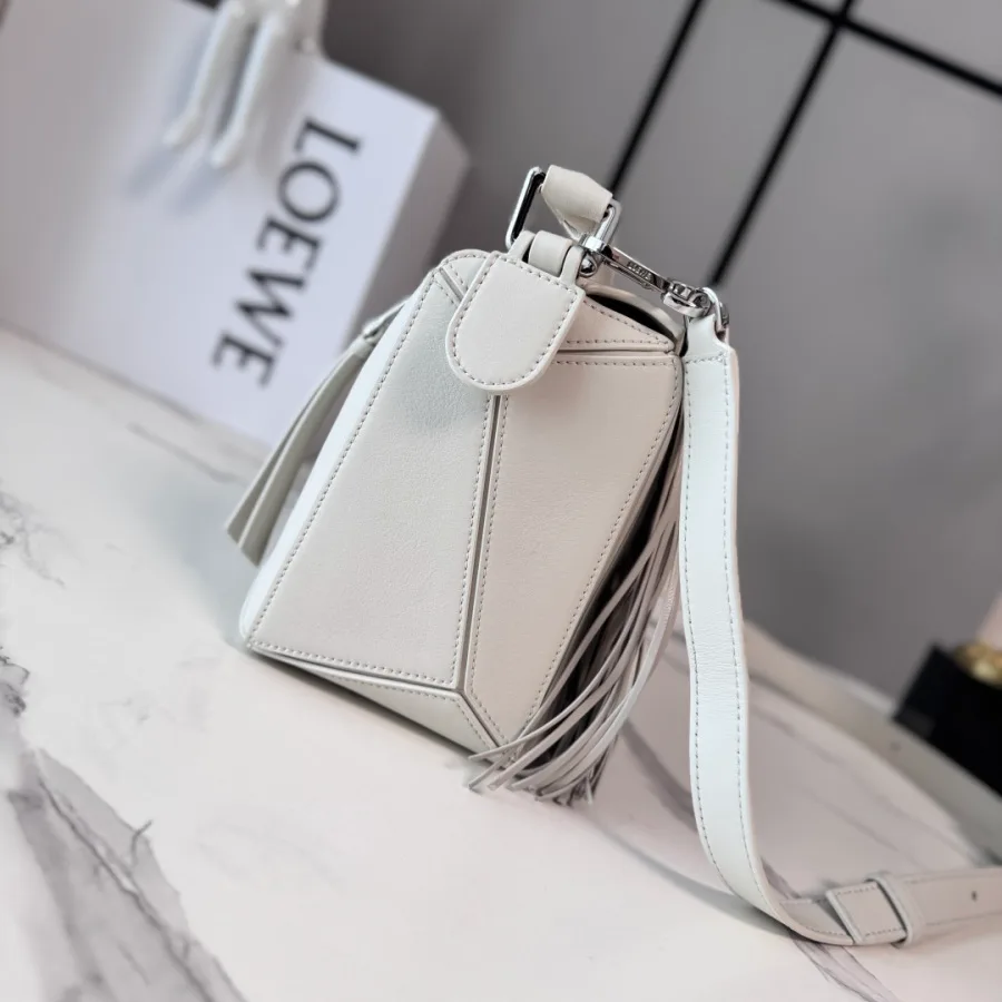 Off-white LOEWE Puzzle-style crossbody bag with stitched geometric panels, a long side fringe and a flat adjustable strap