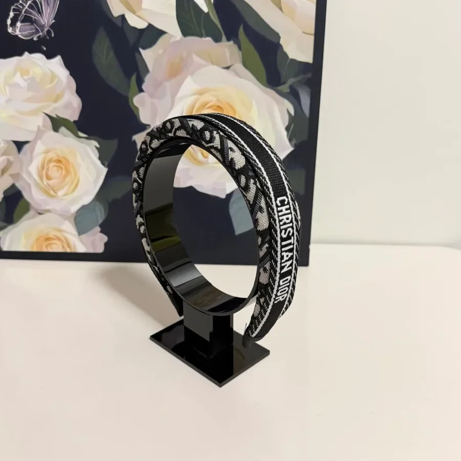 Black canvas Dior belt with leather trim, laid out to show the full strap length and the buckle