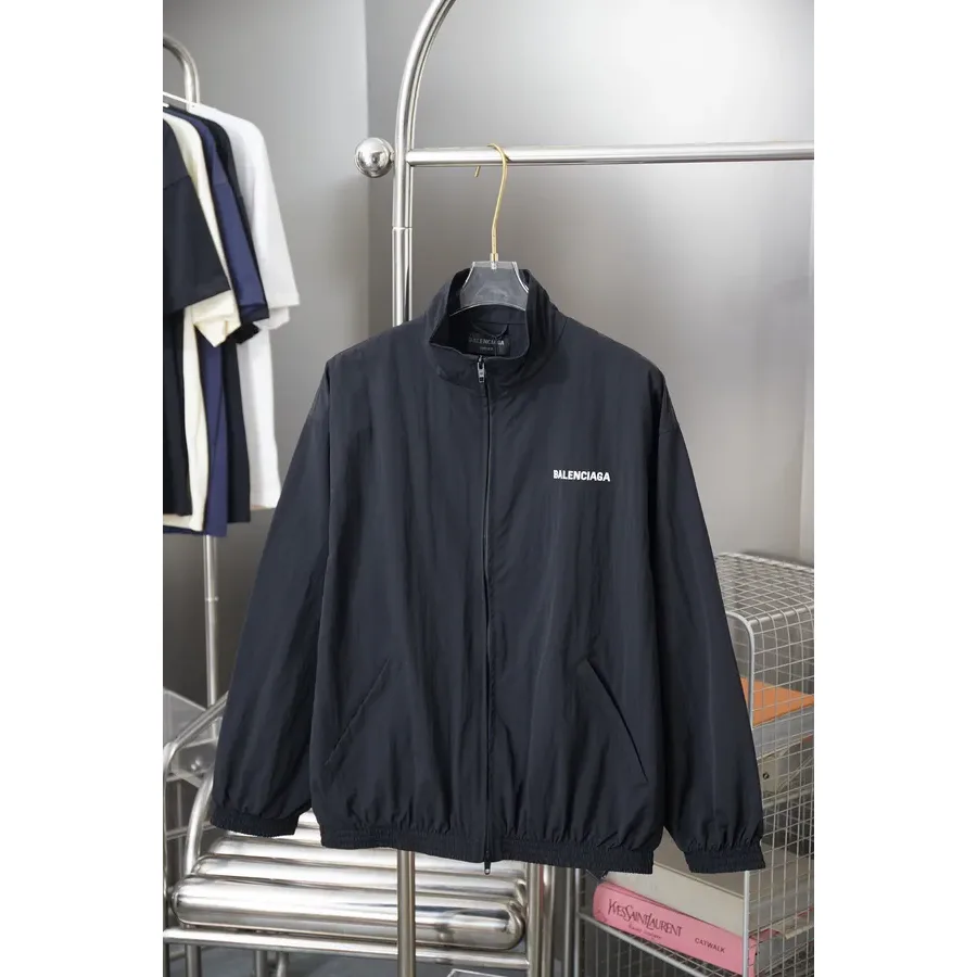Black zip-up jacket with a stand collar and a white logo on the left chest, photographed flat