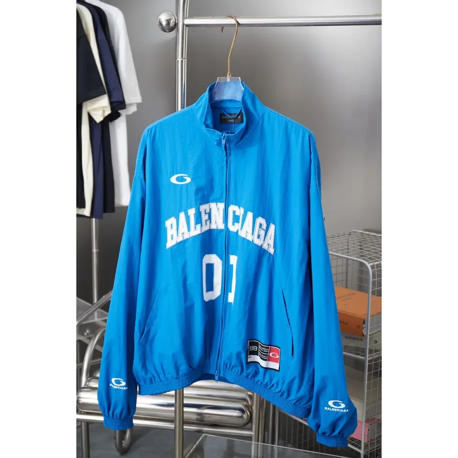 Blue zip-up jacket with a stand collar, gold-tone zipper and white text on the chest