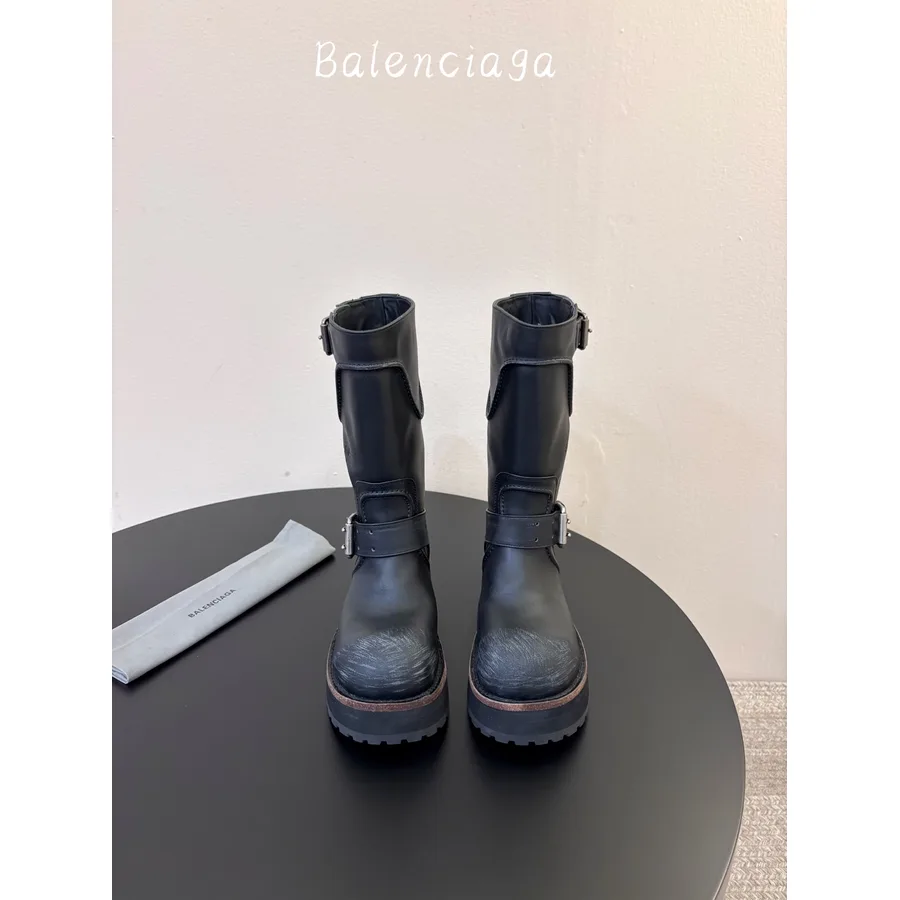 Black mid-calf boot with a round toe, buckled straps over the upper, a wide gusset at the front and a thick toothed rubber outsole