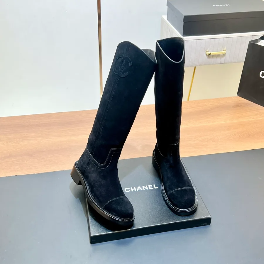 Black suede Chanel boot at a three-quarter angle, the shaft rising above the ankle