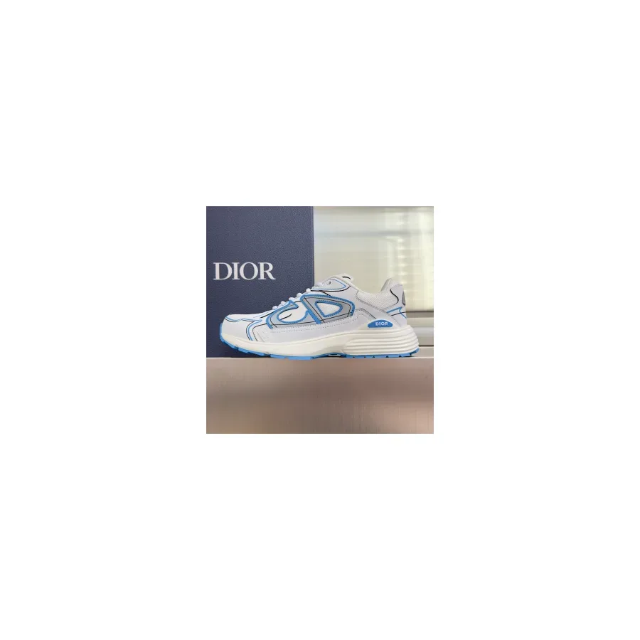 White and blue Dior B30 sneaker shown side-on against a dark blue background, with blue overlay panels across the quarter