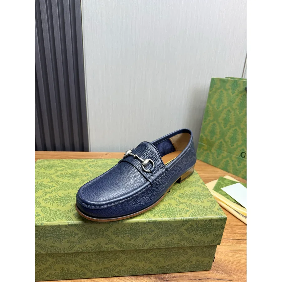 Navy leather loafer with a silver horsebit, shown from a raised angle against packaging
