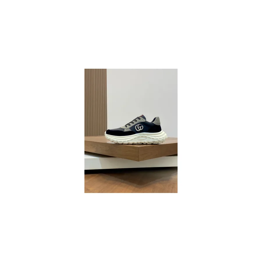 Black Gucci Rhyton-style chunky sneaker with an oversized white rubber sole and a double G metal logo on the side, photographed against a plain background