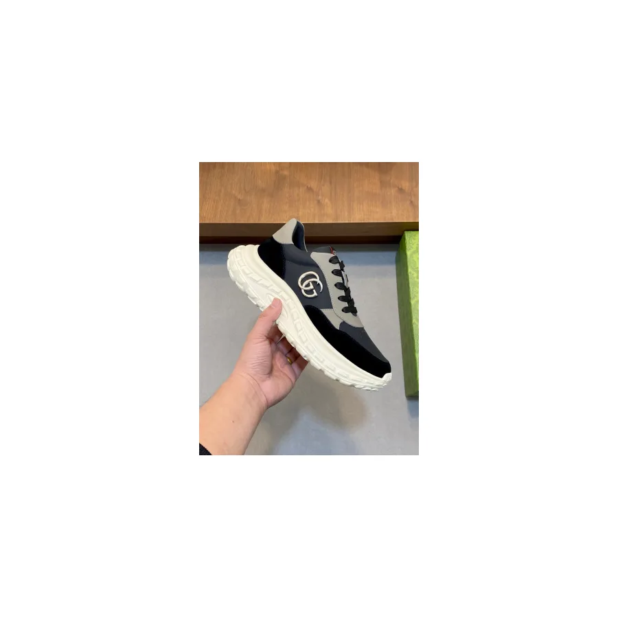 Black Gucci Rhyton-style sneaker photographed from the side, showing the deep white midsole, laces and the metal double G logo on the upper