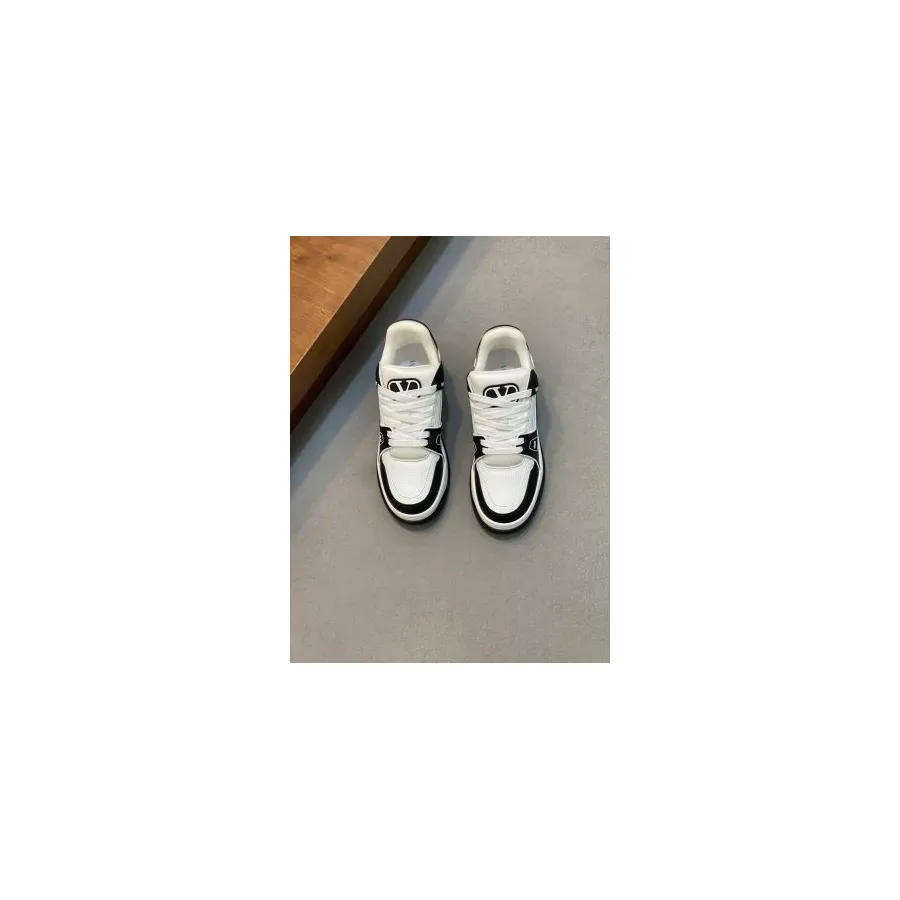 White low-top sneakers with black trim along the sole and heel and a chunky flat sole, photographed as a pair